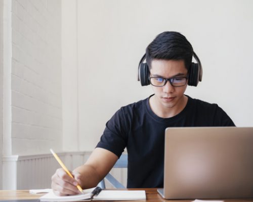 Young  man student study at home. He using laptop and learning online.